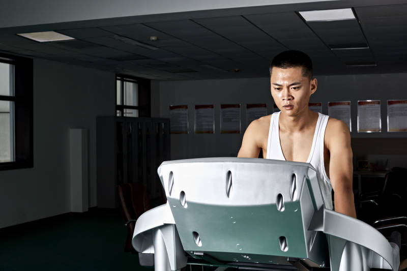在室内用跑步机进行锻炼的亚洲健身男士形象图片