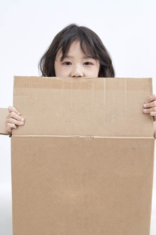 躲在纸箱中玩耍的调皮可爱亚洲小女孩儿童图片