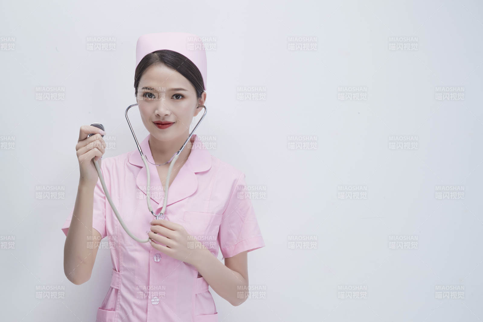 身穿粉色护士服佩戴听诊器的女性医护人员图片