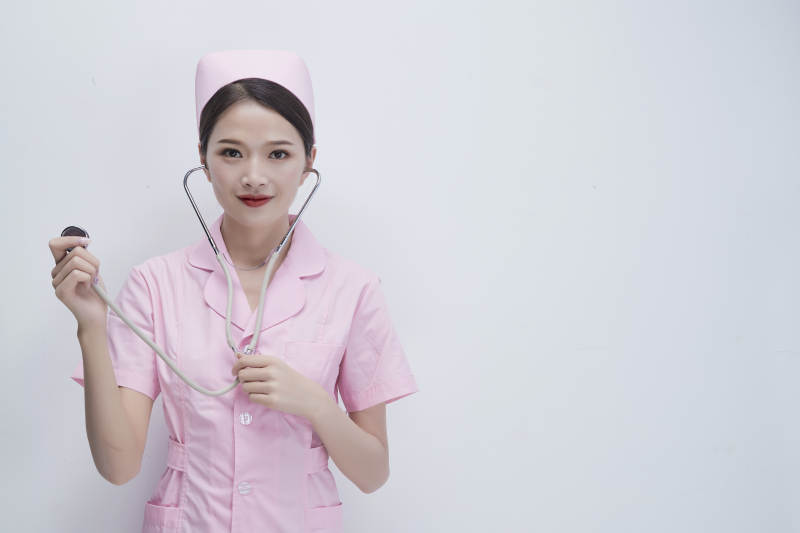 身穿粉色护士服佩戴听诊器的女性医护人员图片