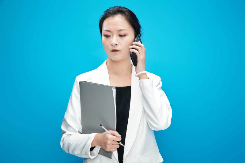 身穿西服拿着手机与文件夹的亚洲商务女士图片