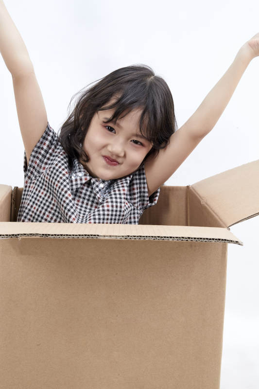 躲在纸箱中玩耍的调皮可爱亚洲小女孩儿童图片