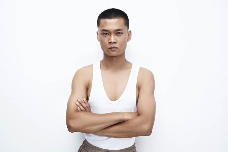 白色背景下展示健身预备拉伸动作的亚洲男性图片