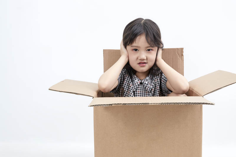 躲在纸箱中玩耍的调皮可爱亚洲小女孩儿童图片