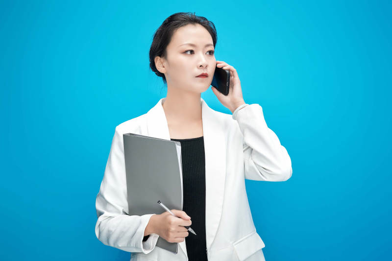 身穿西服拿着手机与文件夹的亚洲商务女士图片