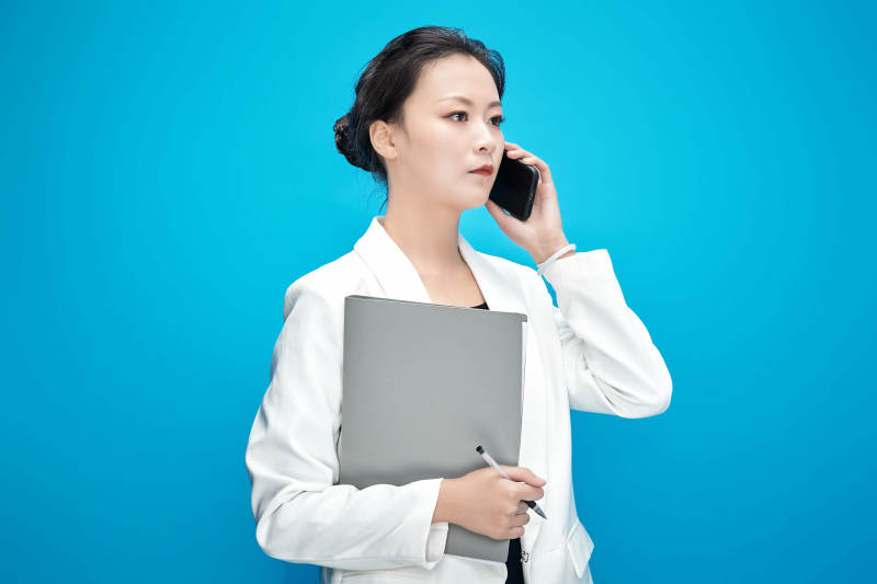 身穿西服拿着手机与文件夹的亚洲商务女士图片