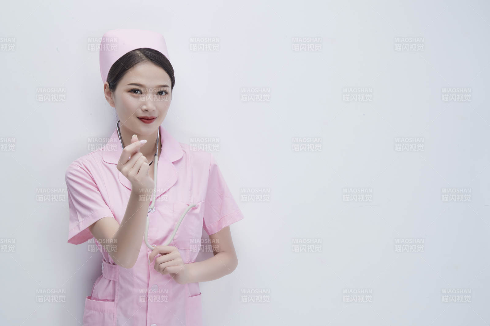 身穿粉色护士服佩戴听诊器的女性医护人员图片