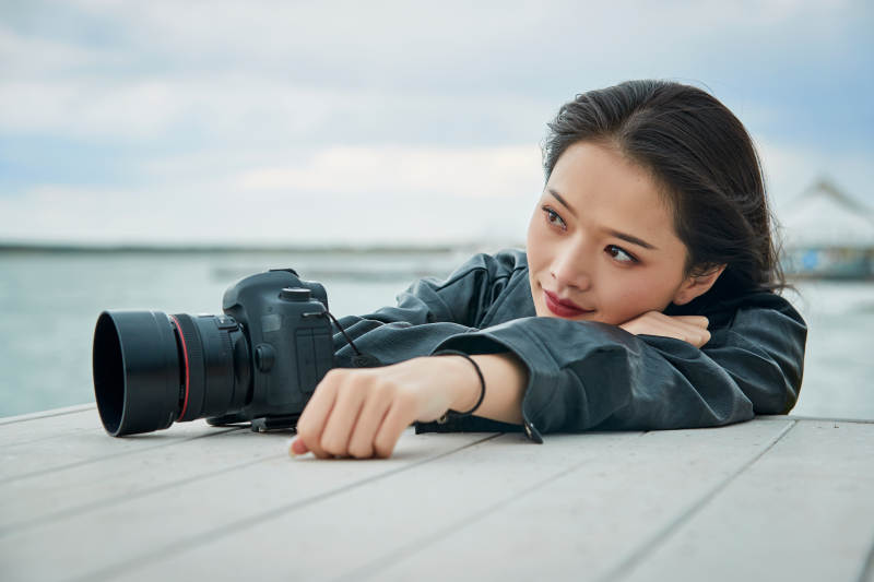 户外湖畔进行拍摄的亚洲青年女性摄影师图片