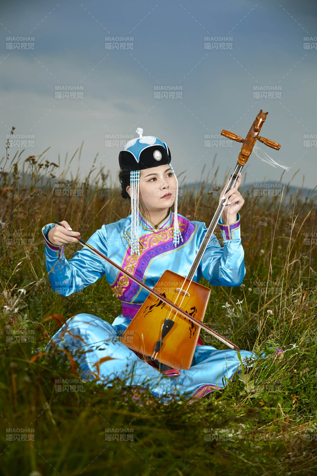 草原上穿蒙古族服饰拉马头琴的蒙族女乐手图片