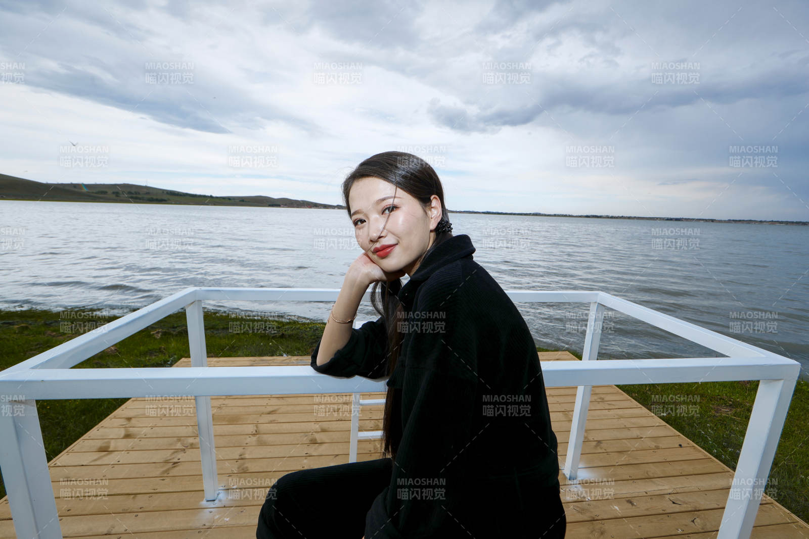 悠闲的坐在美丽湖岸码头的长发少女图片