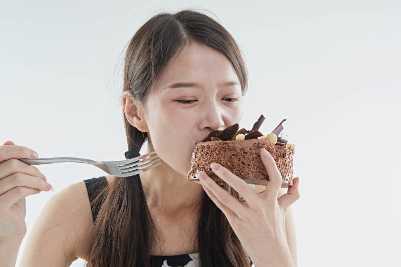 喝红酒品尝蛋糕的年轻女性图片