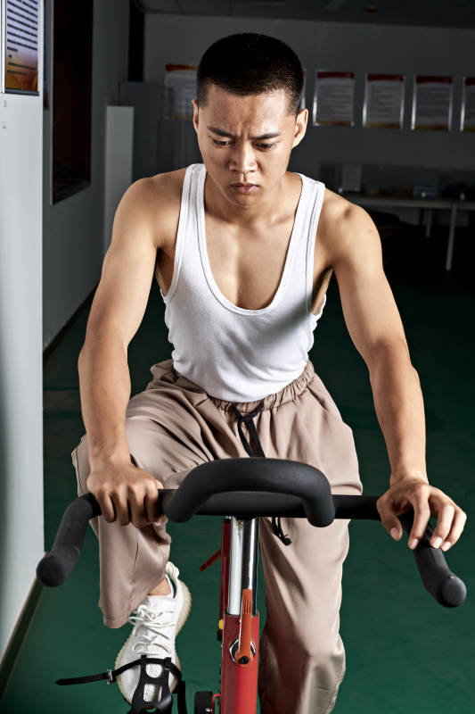 在室内进行动感单车锻炼的亚洲健身男士形象图片