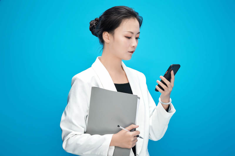 身穿西服拿着手机与文件夹的亚洲商务女士图片