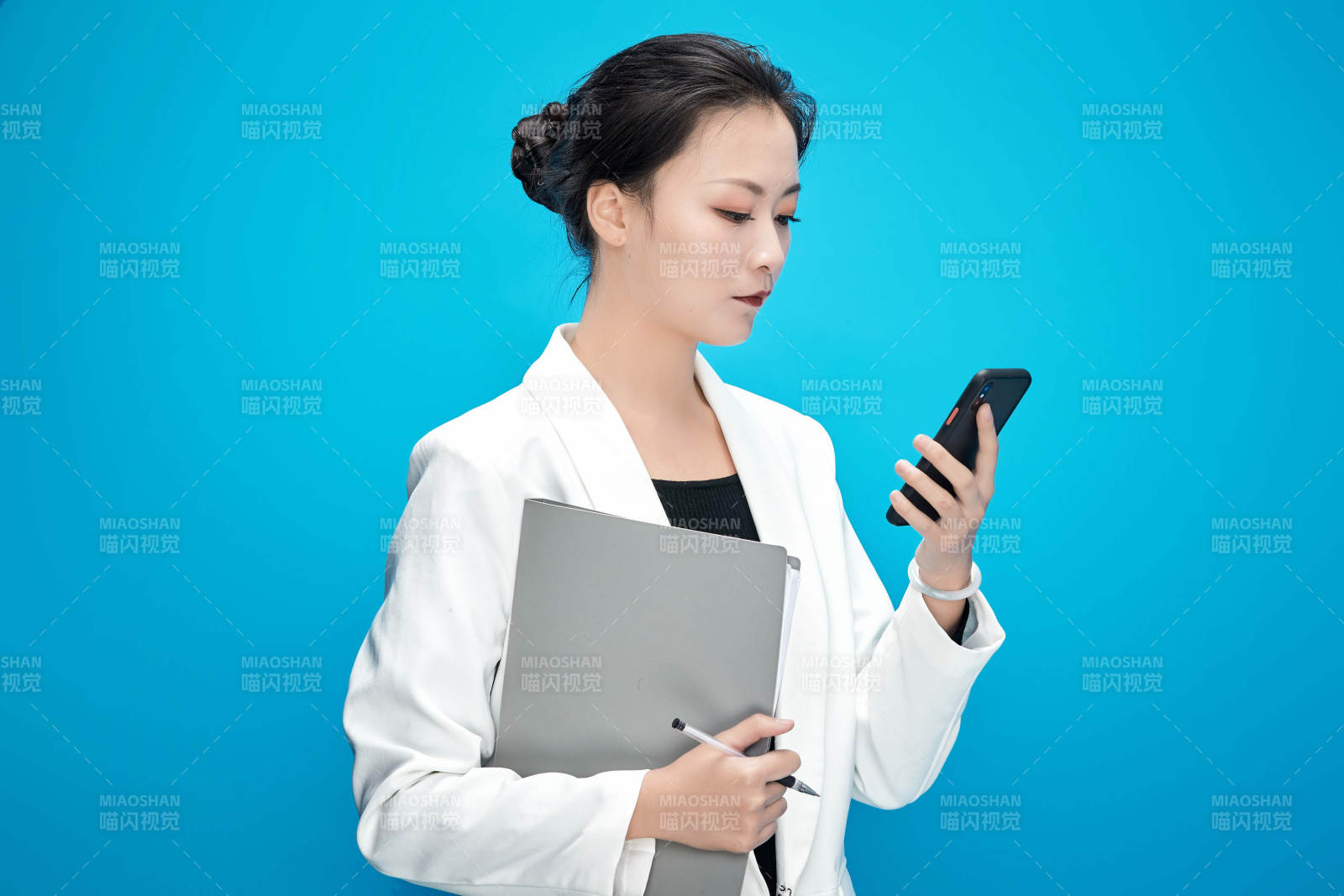 身穿西服拿着手机与文件夹的亚洲商务女士图片