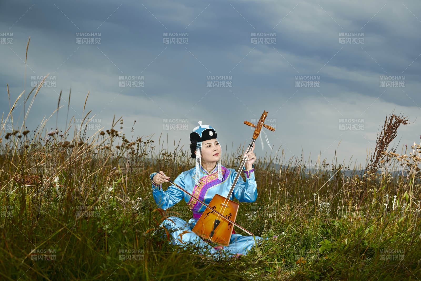 草原上穿蒙古族服饰拉马头琴的蒙族女乐手图片