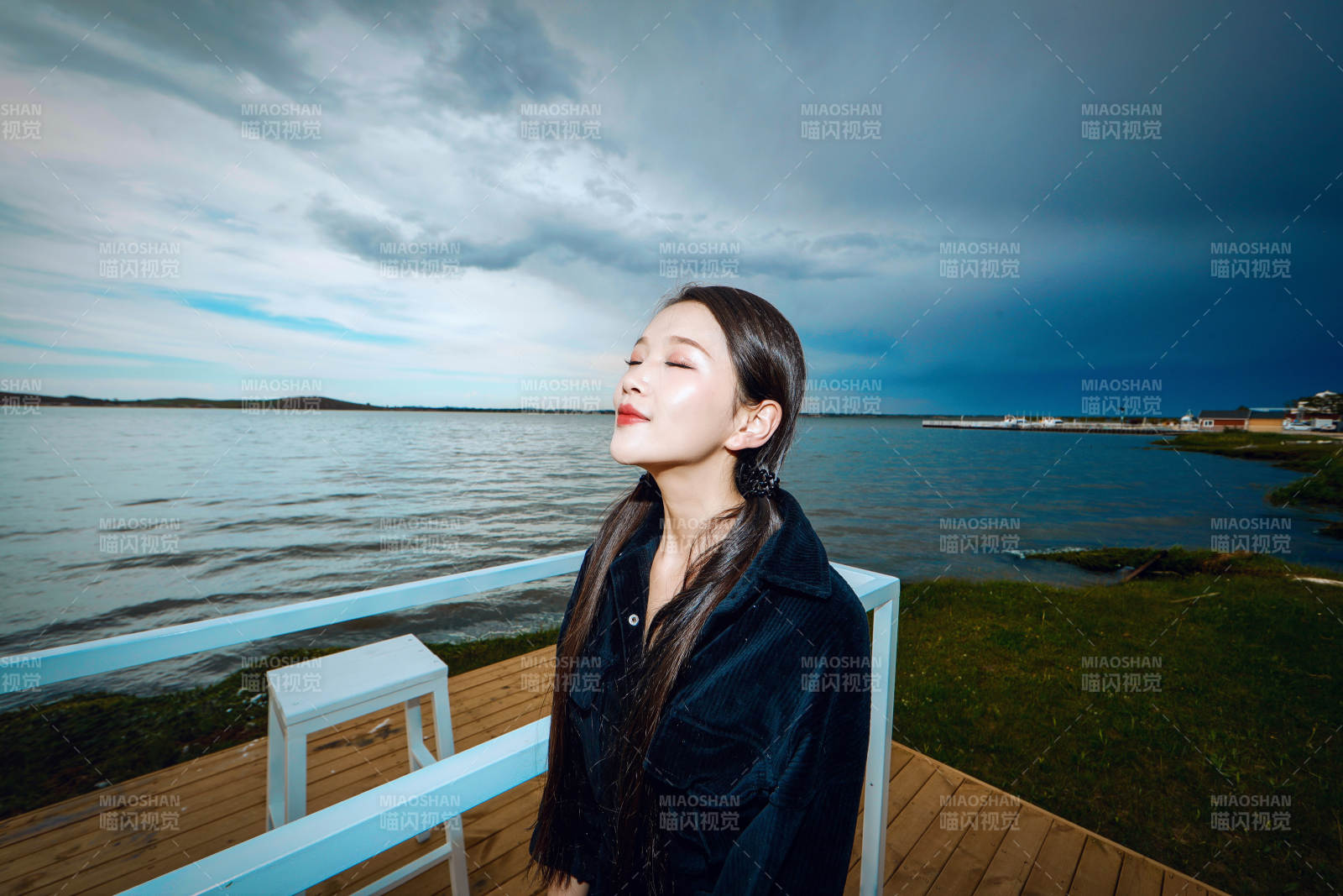 悠闲的坐在美丽湖岸码头的长发少女图片