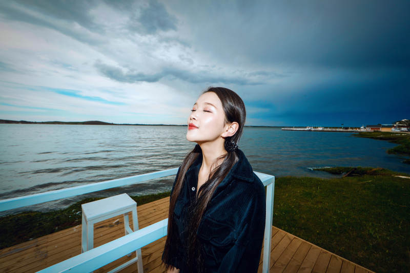 悠闲的坐在美丽湖岸码头的长发少女图片