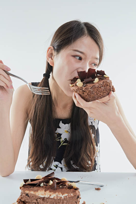 喝红酒品尝蛋糕的年轻女性图片