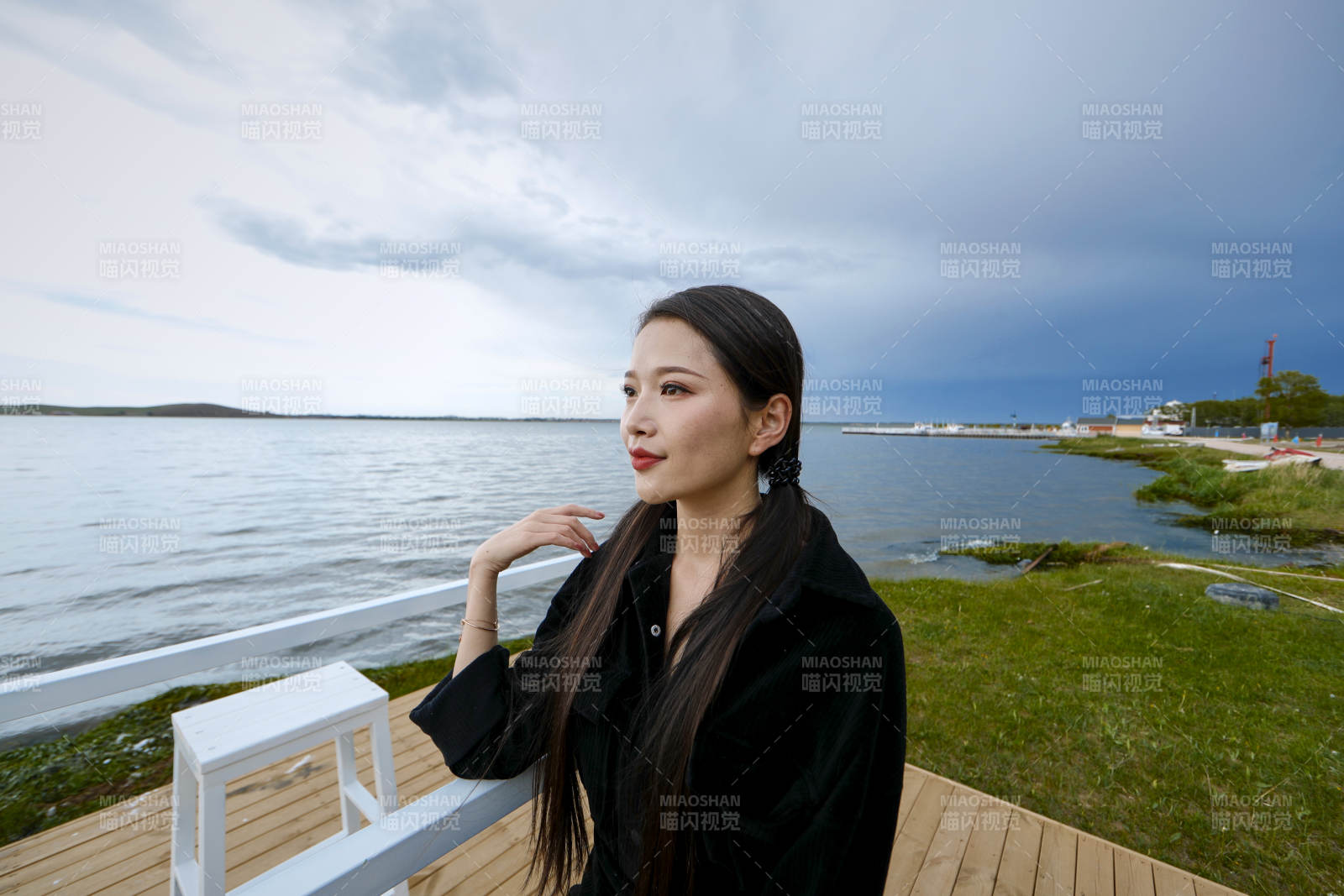 悠闲的坐在美丽湖岸码头的长发少女图片