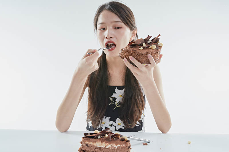 喝红酒品尝蛋糕的年轻女性图片