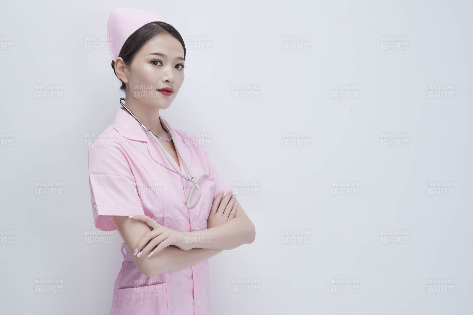 身穿粉色护士服佩戴听诊器的女性医护人员图片