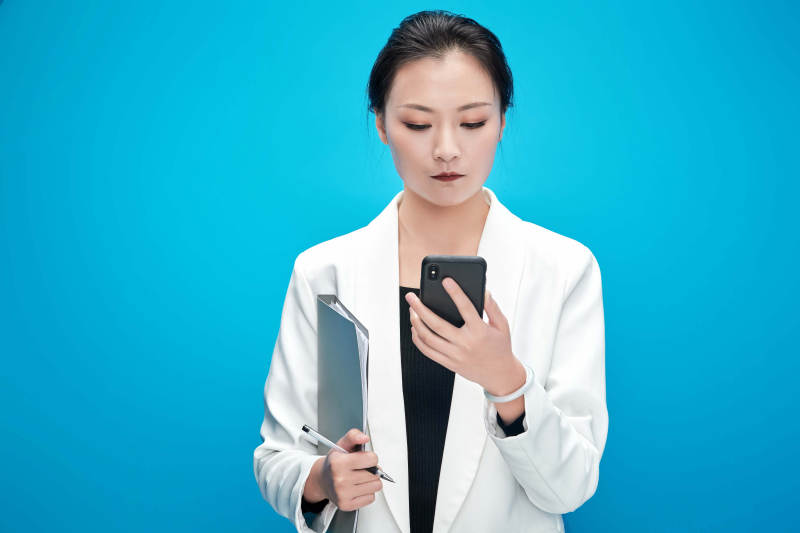 身穿西服拿着手机与文件夹的亚洲商务女士图片