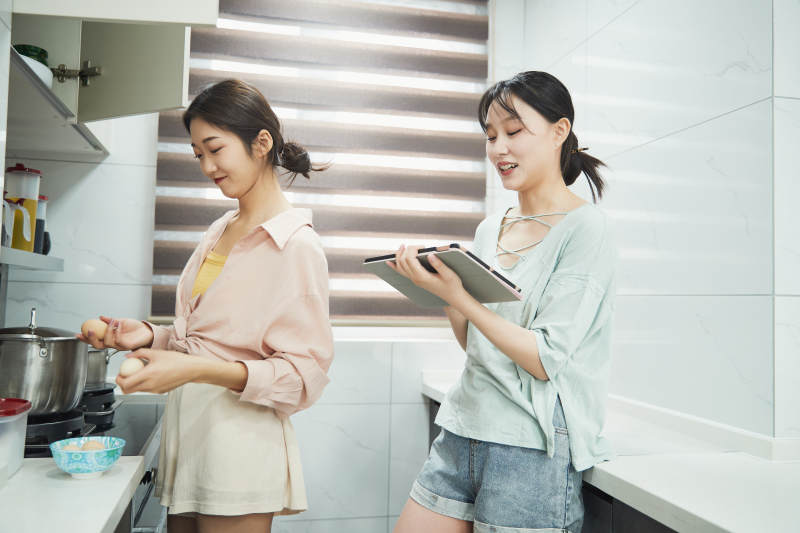 在厨房烹饪美食的亚洲闺蜜少女图片