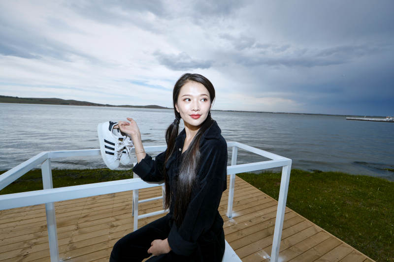 悠闲的坐在美丽湖岸码头的长发少女图片