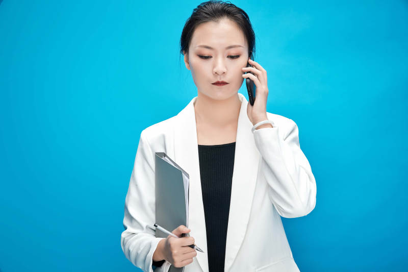 身穿西服拿着手机与文件夹的亚洲商务女士图片