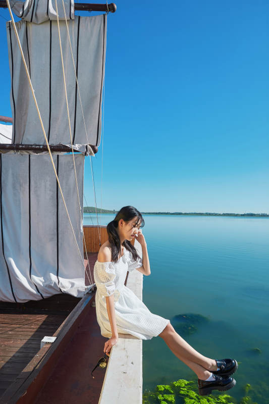 在湖畔木制帆船上的亚洲美女图片