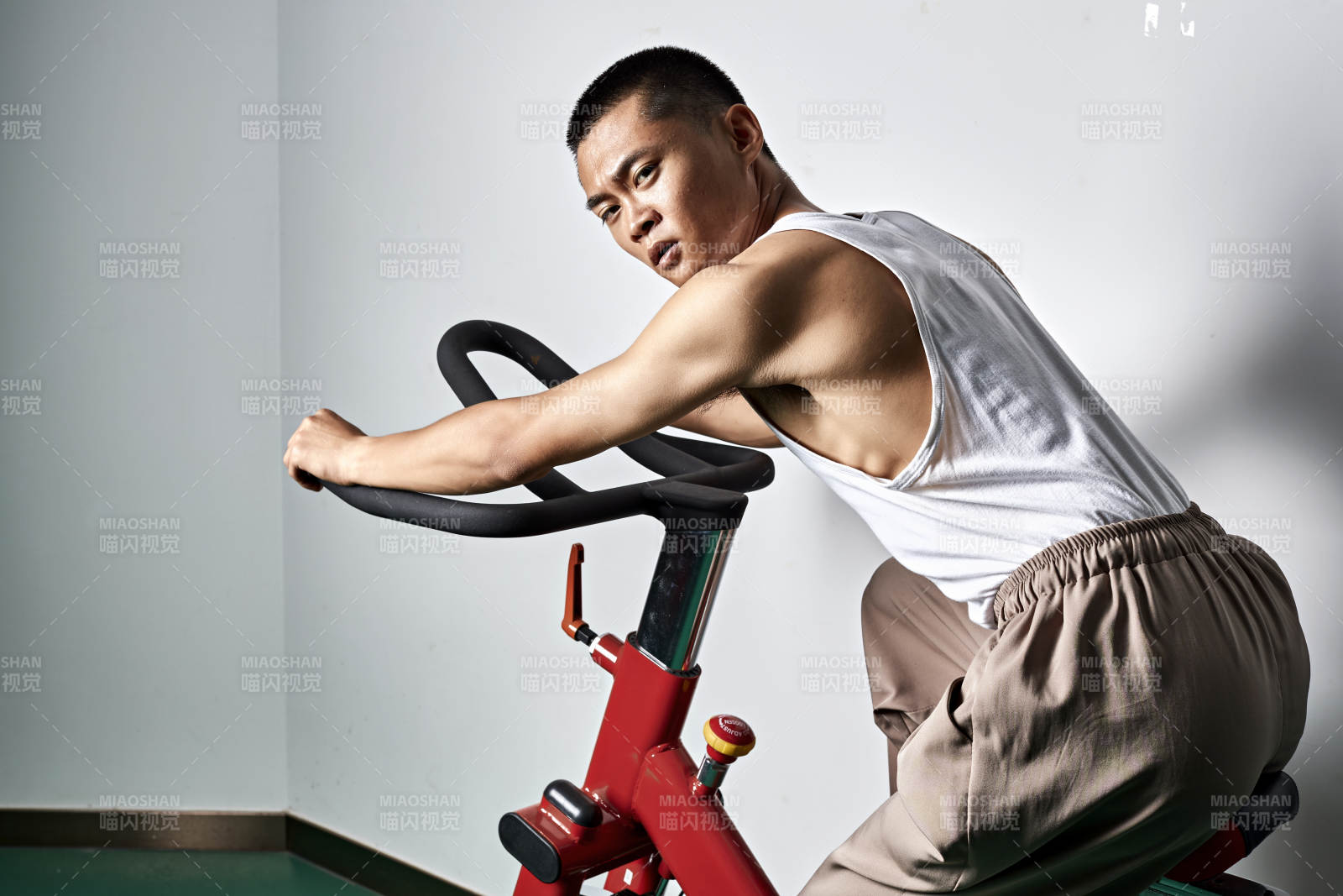 在室内进行动感单车锻炼的亚洲健身男士形象图片