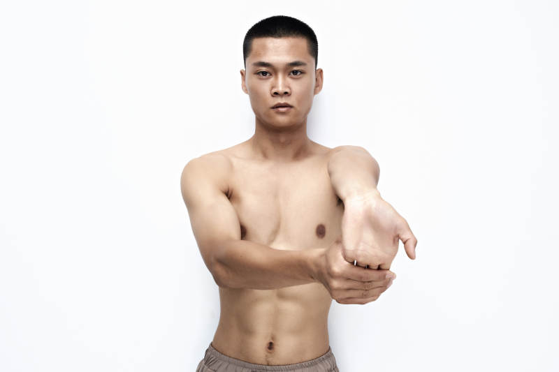 白色背景下展示健身预备拉伸动作的亚洲男性图片