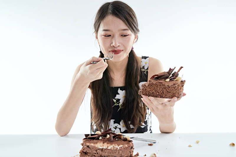 喝红酒品尝蛋糕的年轻女性图片