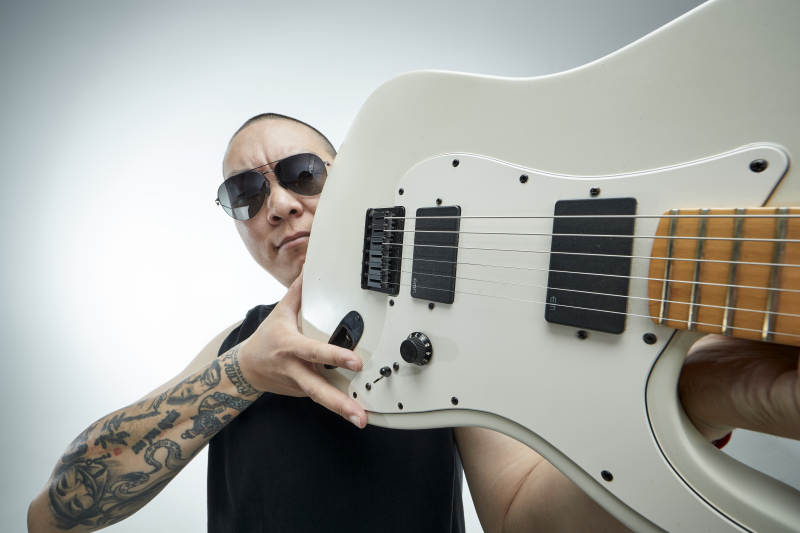 手持电吉他展示演奏的亚洲男性摇滚乐手人像图片