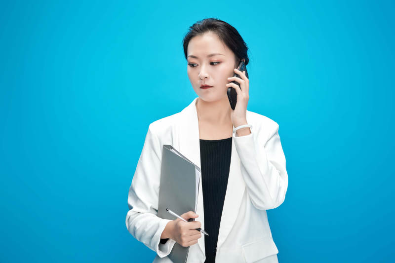 身穿西服拿着手机与文件夹的亚洲商务女士图片