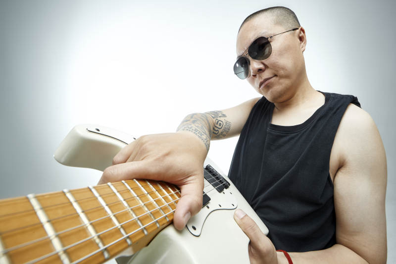 手持电吉他展示演奏的亚洲男性摇滚乐手人像图片