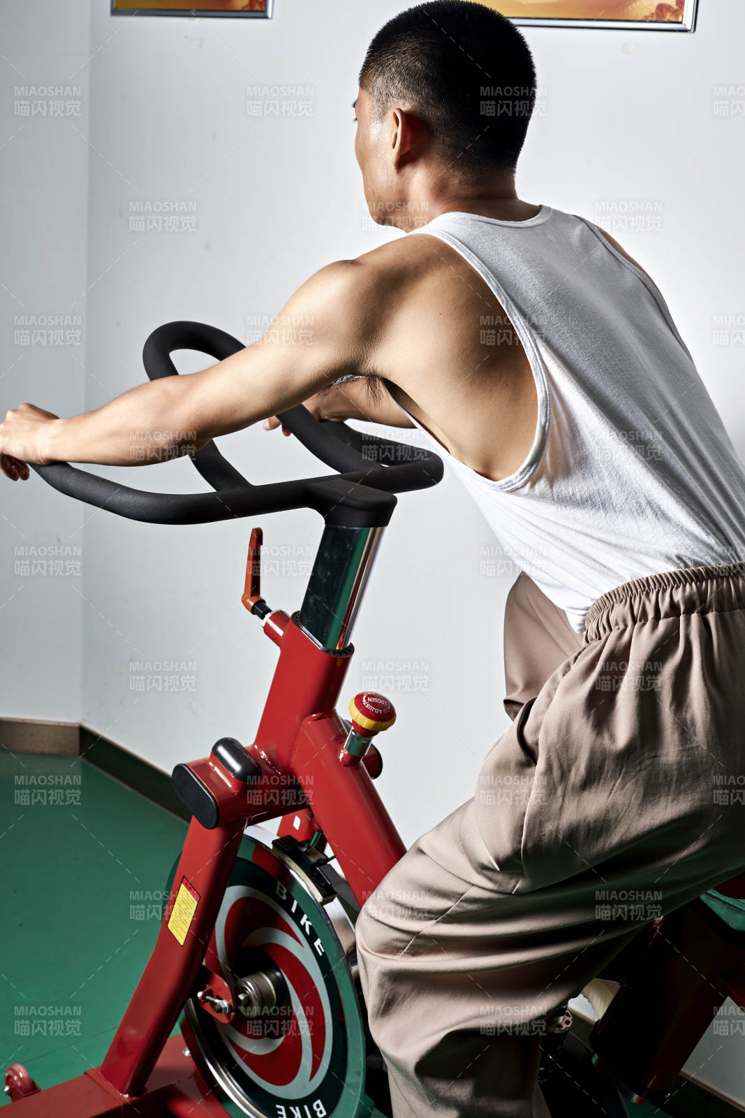 在室内进行动感单车锻炼的亚洲健身男士形象图片