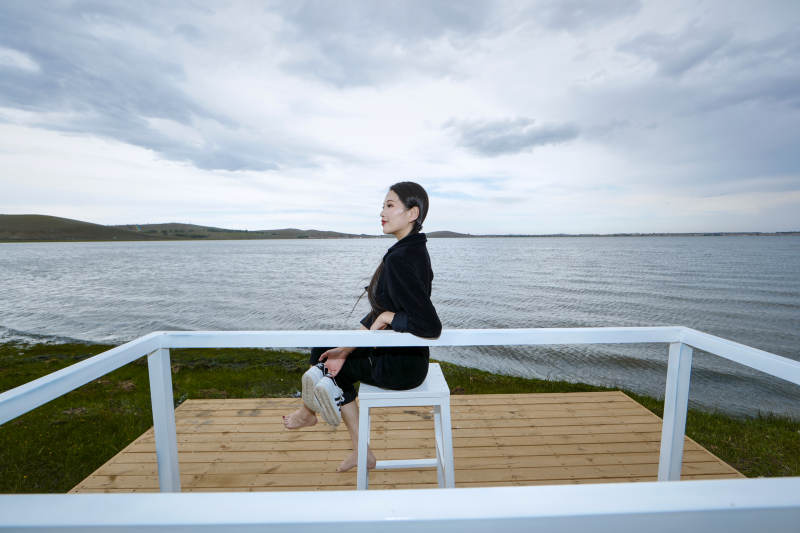 悠闲的坐在美丽湖岸码头的长发少女图片