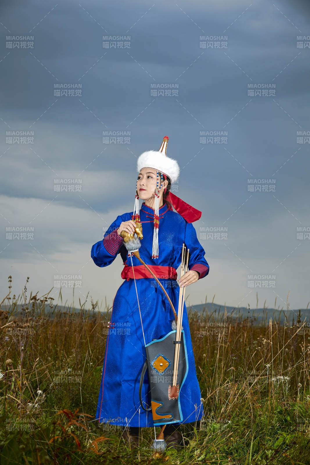 草原湖畔身穿蒙古族饰手持弓箭的蒙族少女图片