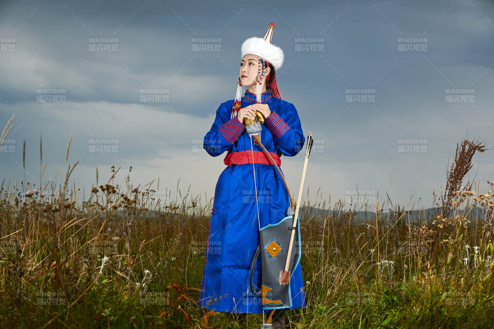 草原湖畔身穿蒙古族饰手持弓箭的蒙族少女图片