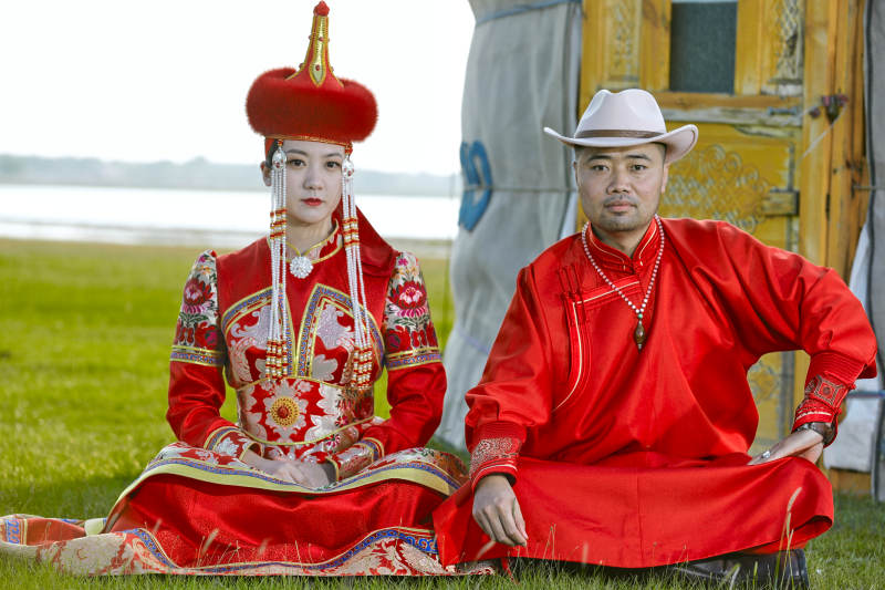 草原上蒙古包前穿蒙古族传统服饰的年轻夫妻图片