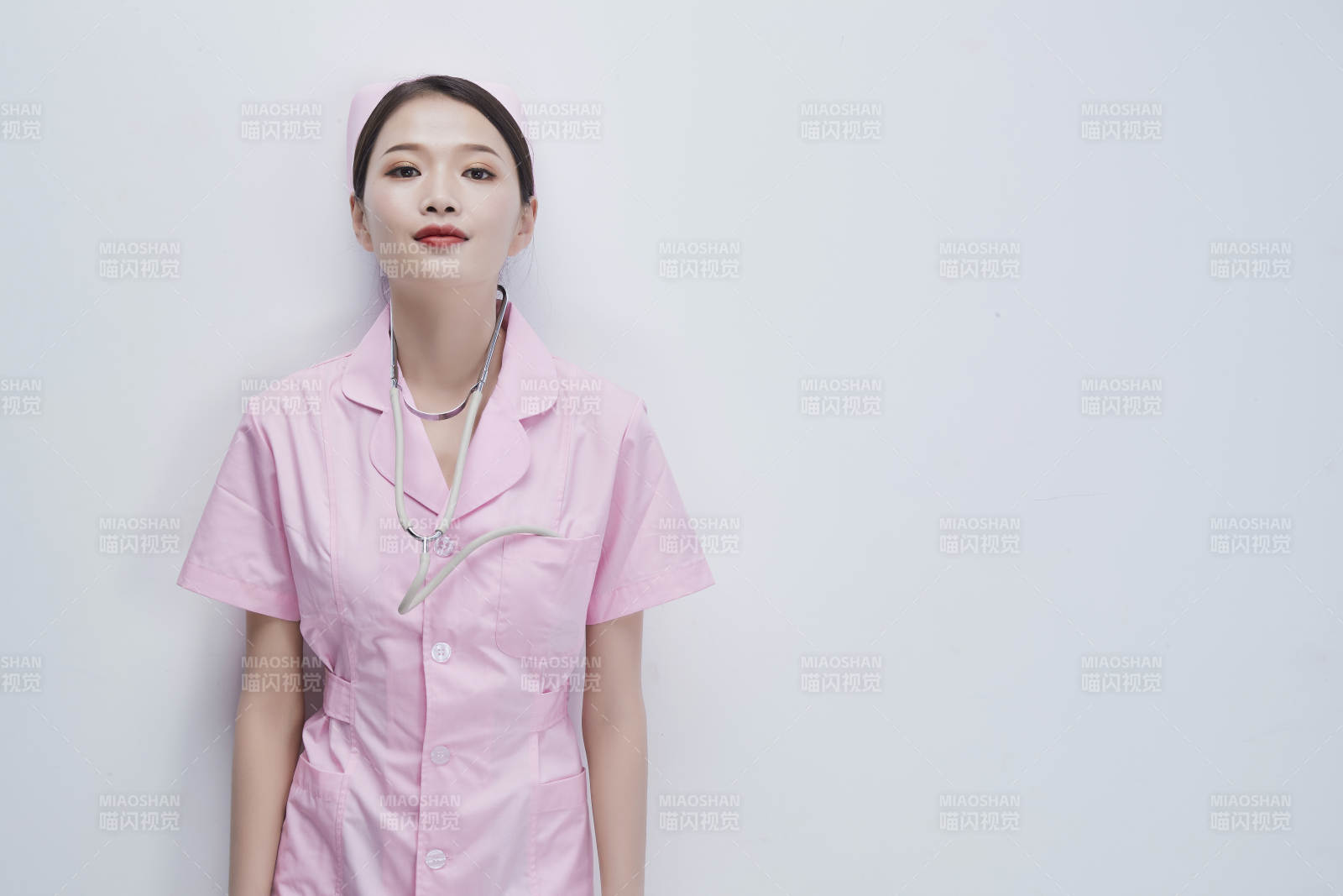 身穿粉色护士服佩戴听诊器的女性医护人员图片