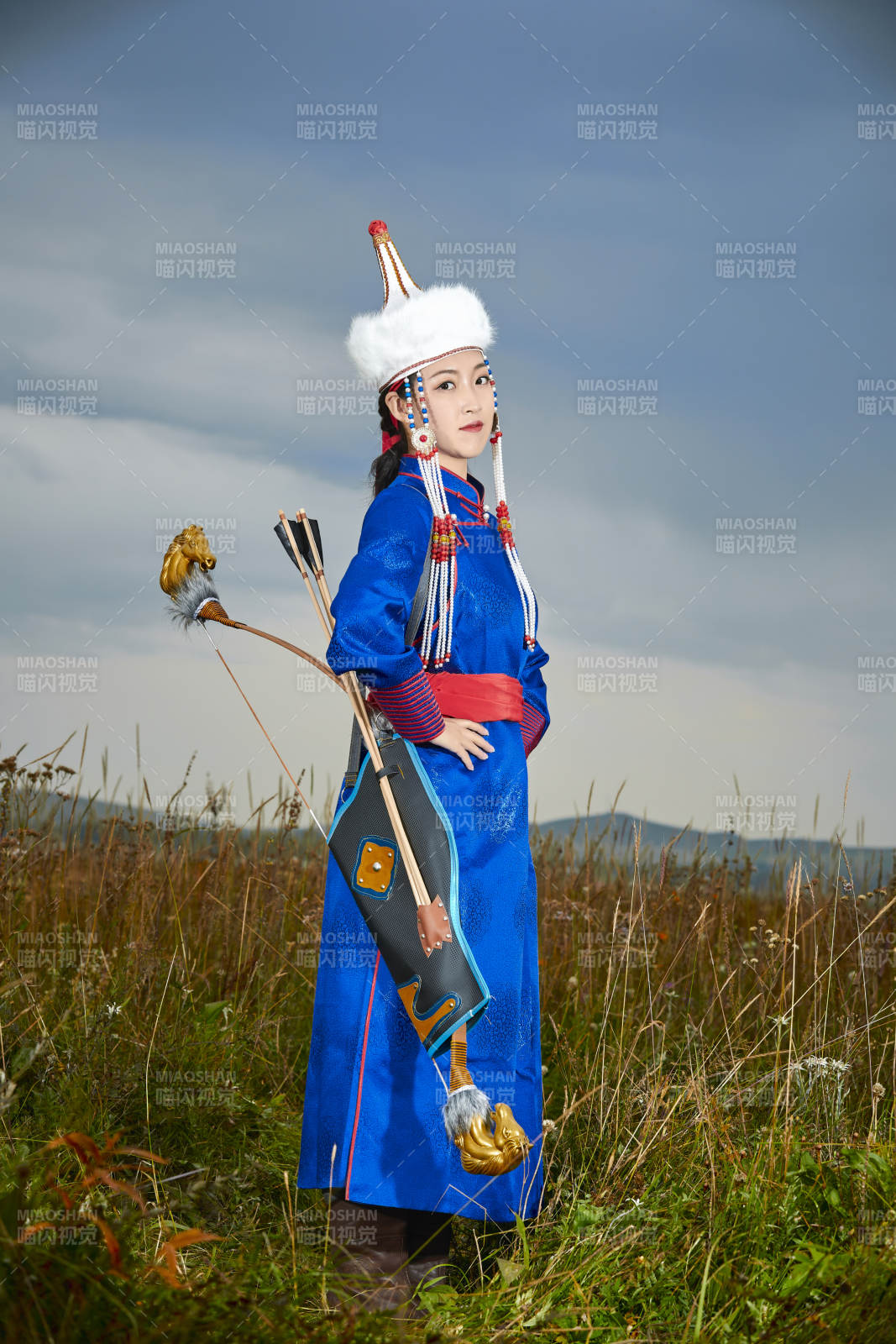 草原湖畔身穿蒙古族饰手持弓箭的蒙族少女图片