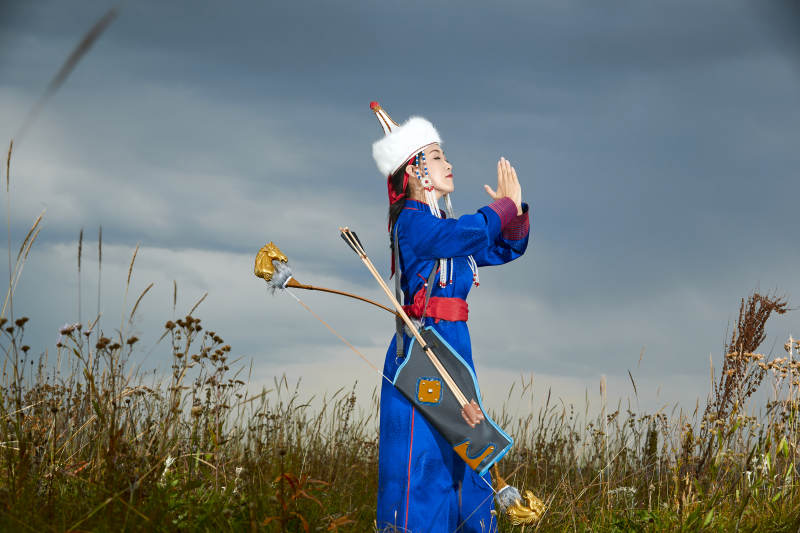 草原湖畔身穿蒙古族饰手持弓箭的蒙族少女图片