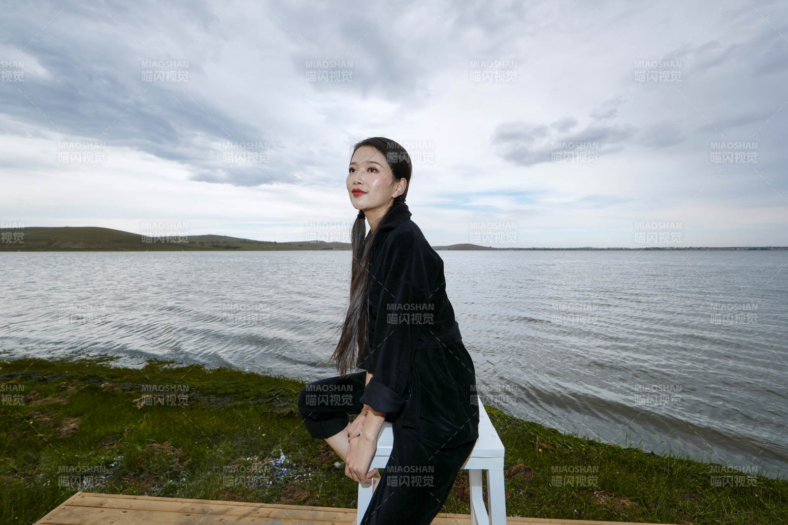 悠闲的坐在美丽湖岸码头的长发少女图片