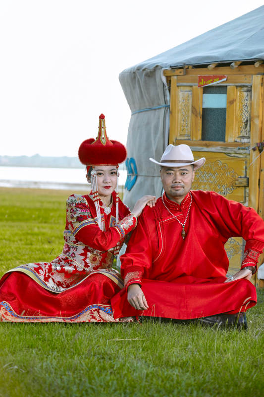 草原上蒙古包前穿蒙古族传统服饰的年轻夫妻图片