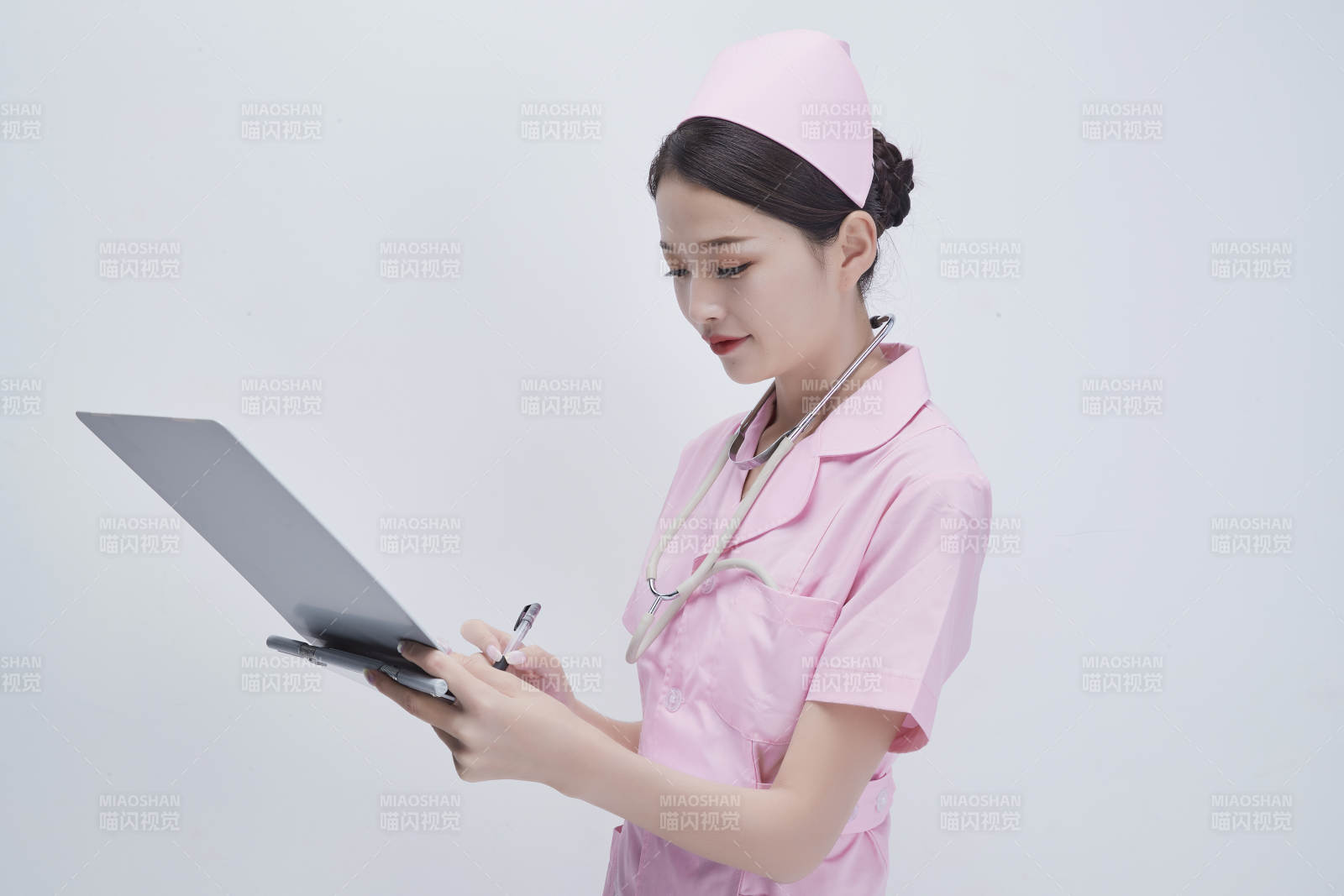 穿粉色护士服戴听诊器手持病历夹的医护人员图片