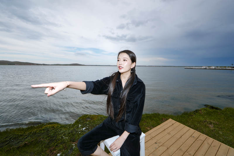 悠闲的坐在美丽湖岸码头的长发少女图片