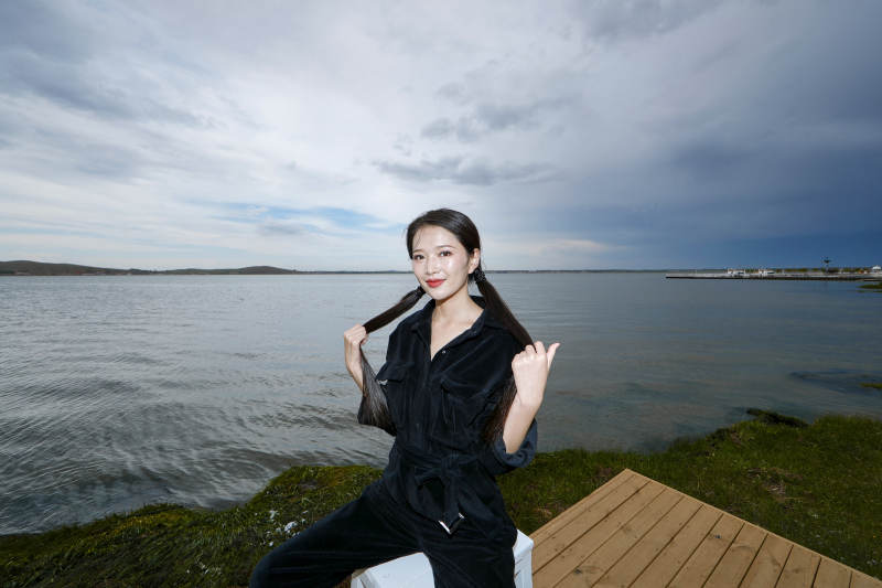 悠闲的坐在美丽湖岸码头的长发少女图片