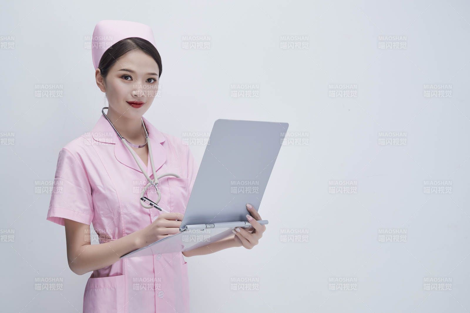 穿粉色护士服戴听诊器手持病历夹的医护人员图片